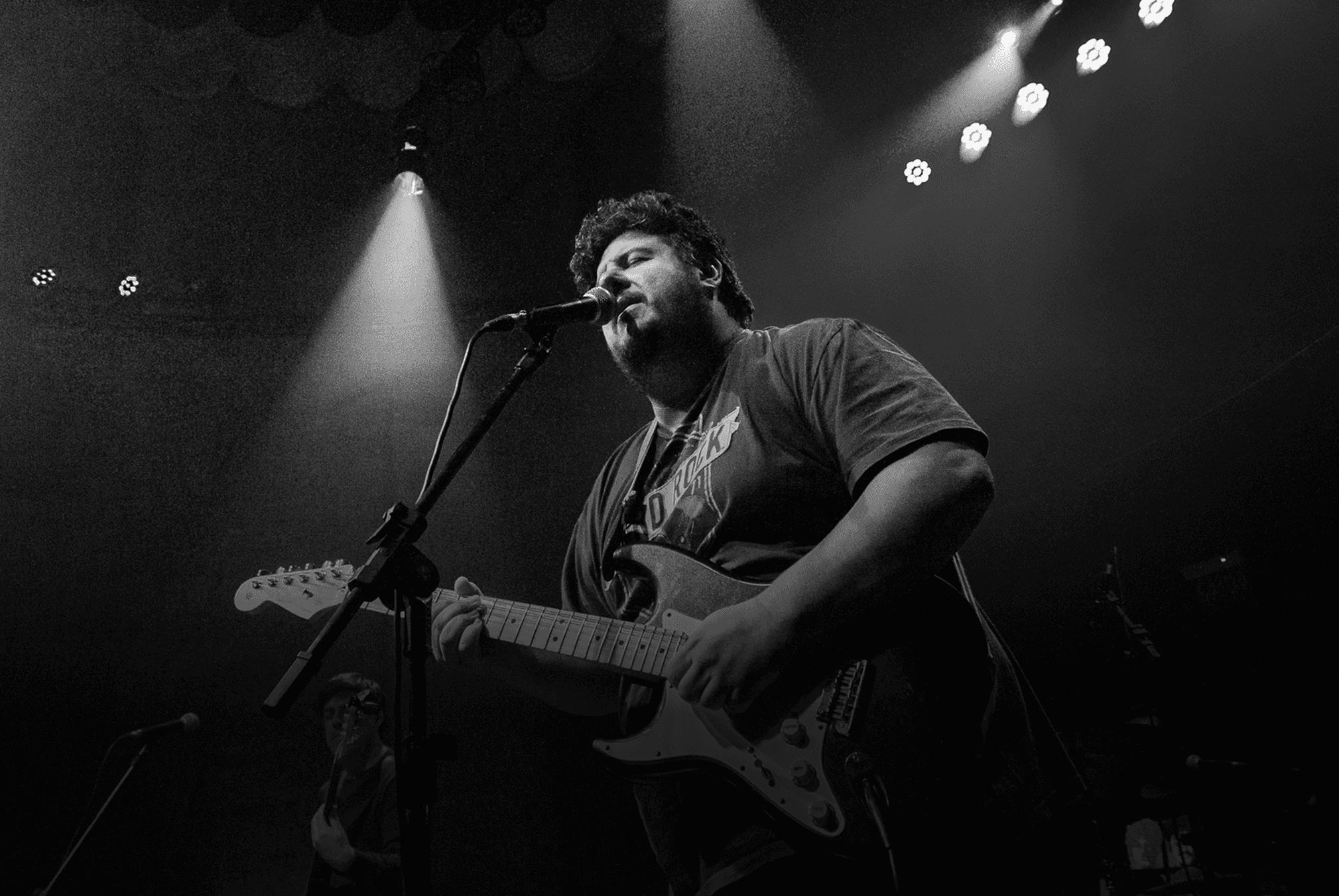 International blues guitarist performing live on stage, singing into the microphone and playing guitar during the show.