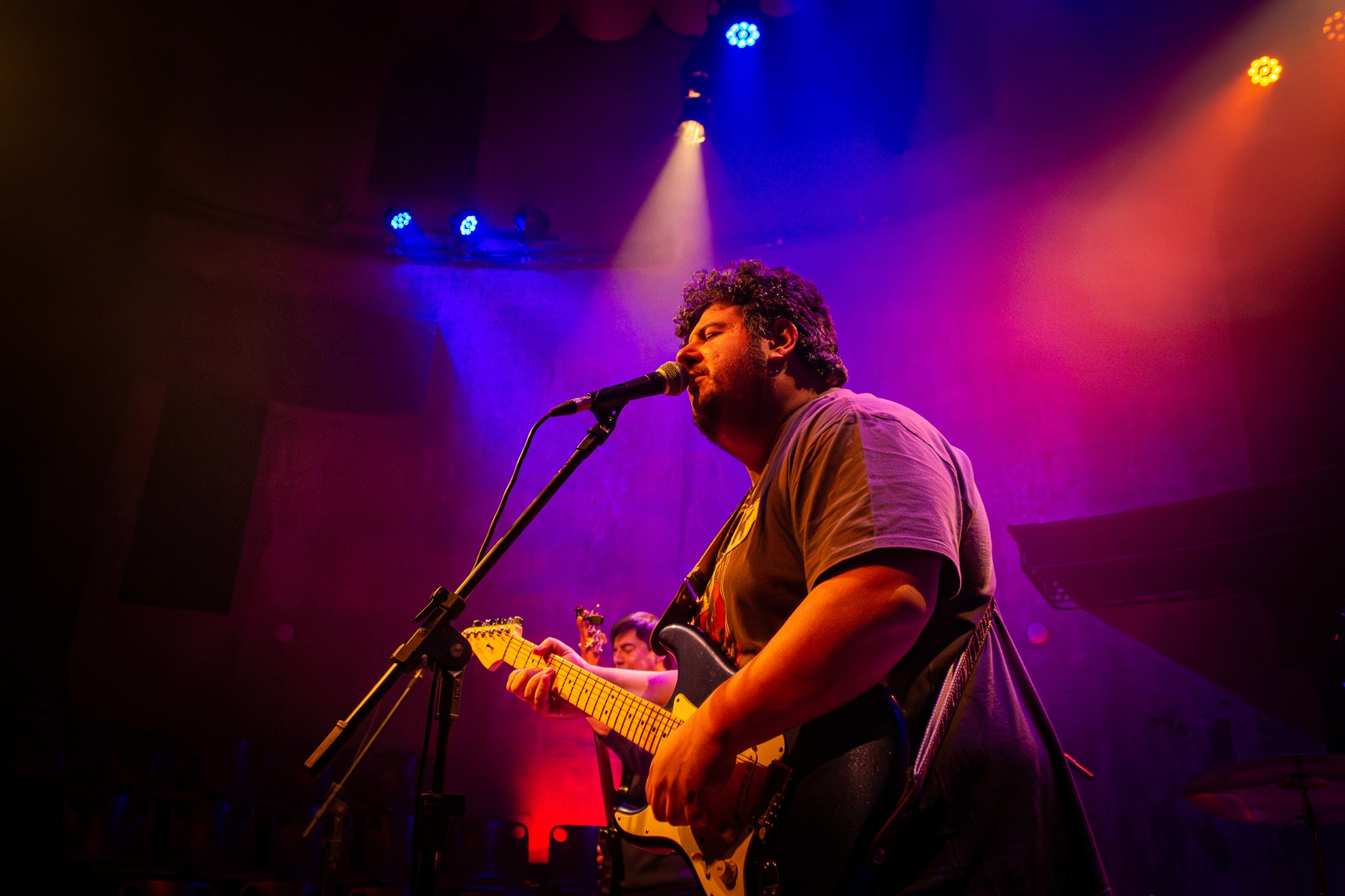 International blues guitarist performing live on stage, singing into the microphone and playing guitar during the show.