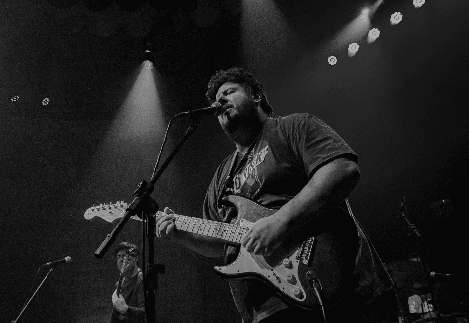 International blues guitarist performing live on stage, singing into the microphone and playing guitar during the show.