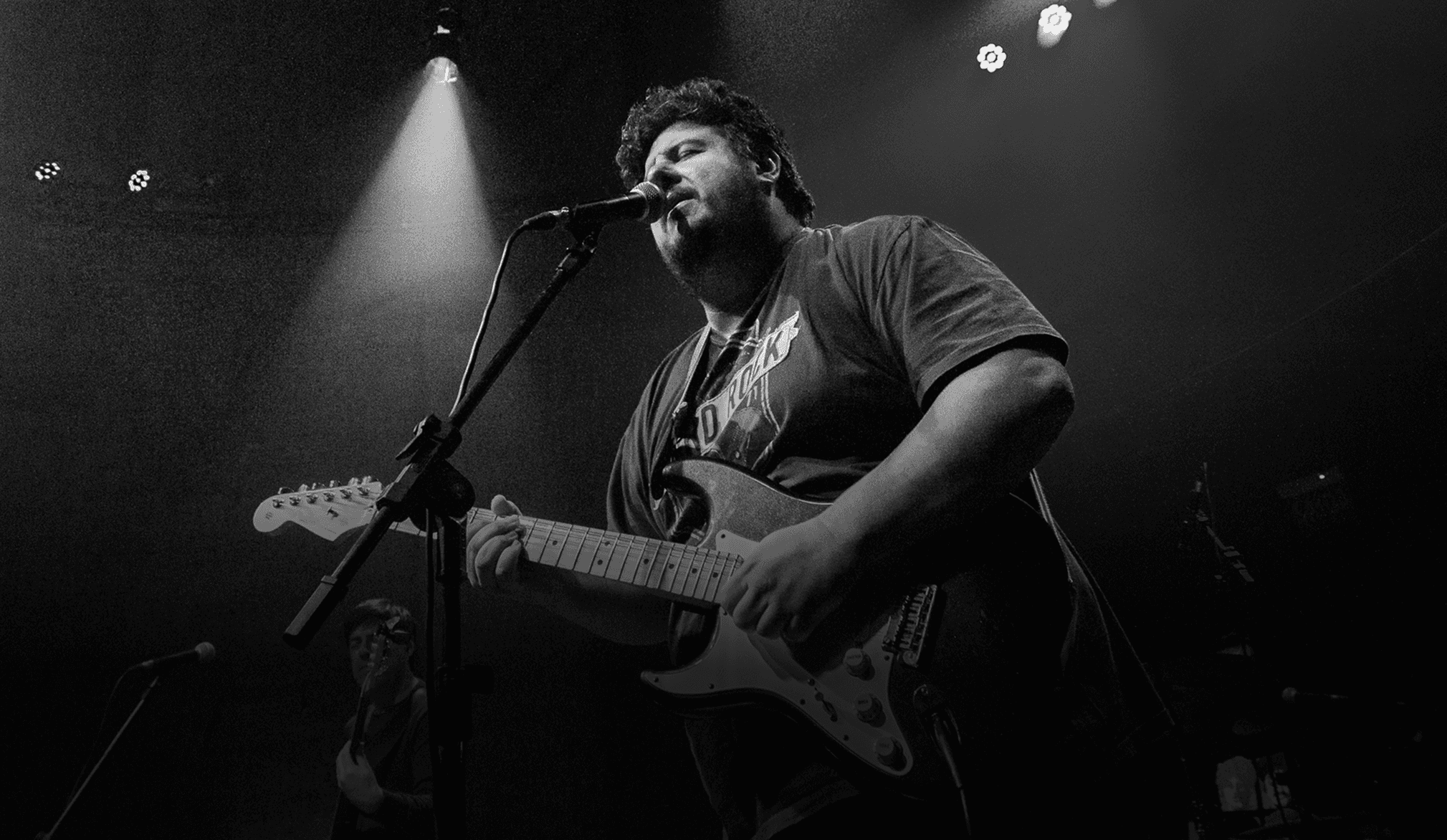 International blues guitarist performing live on stage, singing into the microphone and playing guitar during the show.
